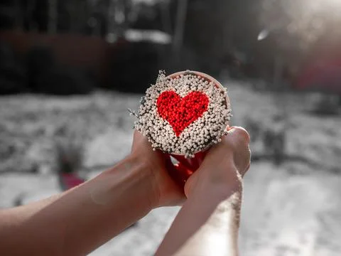 Red heart made of tiny balls in a mug, top view, photo black and white only r Stock Photos