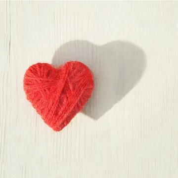 Red heart made of wool threads on a light wooden background Stock Photos