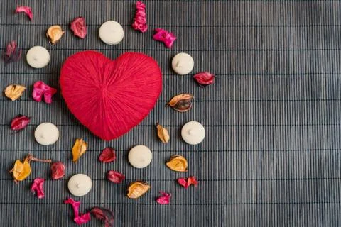 A red heart made of woolen threads lies on a brown bamboo mat. Valentine's Da Stock Photos