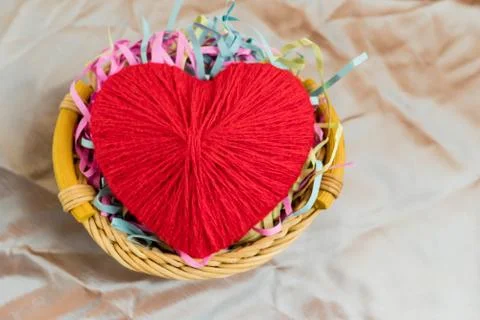 A red heart made of woolen threads lies in a bamboo basket. Valentine's Day. Stock Photos