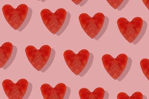 Red heart pattern cut from ripe watermelon on pink background with hard shado Stock Photos