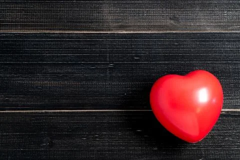 The red heart is placed on the left side of the black wood table. Copy space  Stock-Fotos