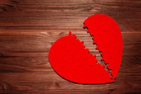 Red Heart Puzzle Split in Half on a Wooden Table 스톡 사진