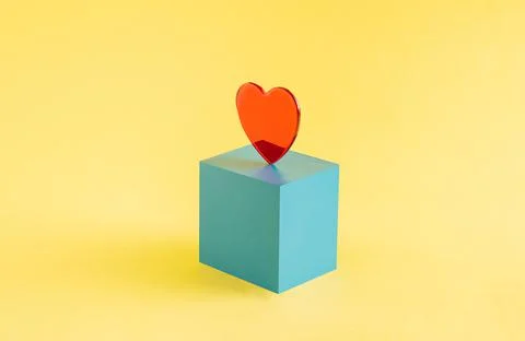 A red heart set on a blue cube isolated on a yellow background. Valentine's Day Stock Illustration