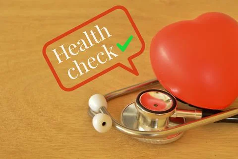 Red heart shape and stethoscope with text HEALTH CHECK. Stock Photos