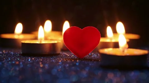 Red heart shape with burning candles on shimmering dark background Stock Footage 334572323