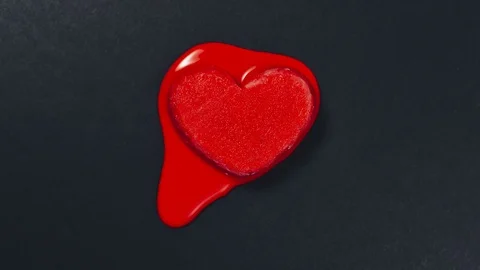 Red heart shape ice cream melting on dark or black textured paper background Stock Footage 93579480