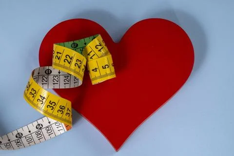 Red heart shape with measuring tape symbolizing health care Stock Photos
