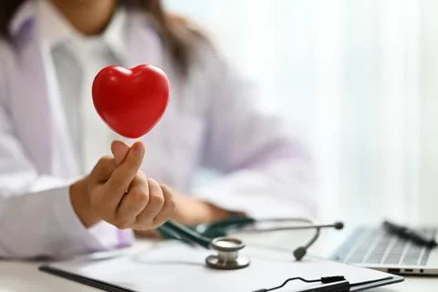 Red heart shape over female doctor hand. Cardiac medical checkup, health care Stock Photos