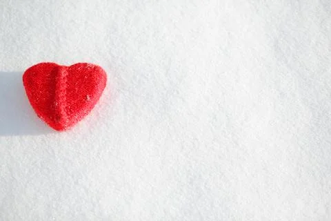 Red heart shape on a snowy background Stock Photos