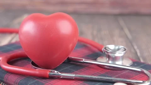 Red heart shape with stethoscope on check patterned diary placed on wooden .. Stock Footage 333153234