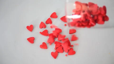 Red heart shaped candy pouring from hampagne glass on the table. Valentine's Day Stock Footage 145121969