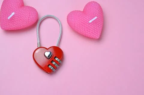 Red heart-shaped code lock. Pink background. Valentine's Day. Candles. Stock Photos