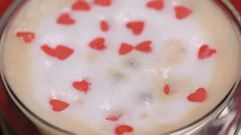 Red heart shaped confetti fall in cappuccino foam Stock Footage 147367387