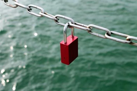 Red heart-shaped locks are hanging on the bridge lovers Stock Photos