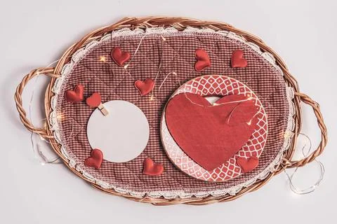 Red heart shaped object placed in a straw salver and round white empty blank on Stock Photos