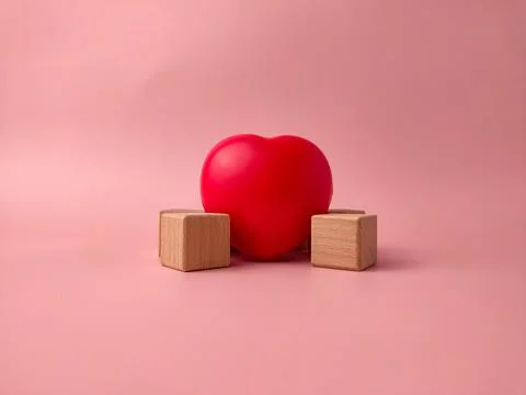 Red heart-shaped object positioned between two small wooden blocks on a pin.. Stock Photos