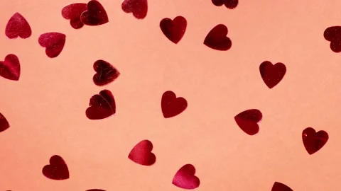 Red heart-shaped sequins are spinning in a circle on a red background Stock Footage 169635357