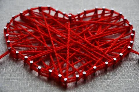 Red heart string art made with tangled yarn on metal nails on canvas background Stock-Fotos