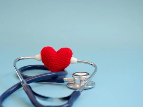 Red heart using deep blue stethoscope on the blue background. Concept of love Stock Photos