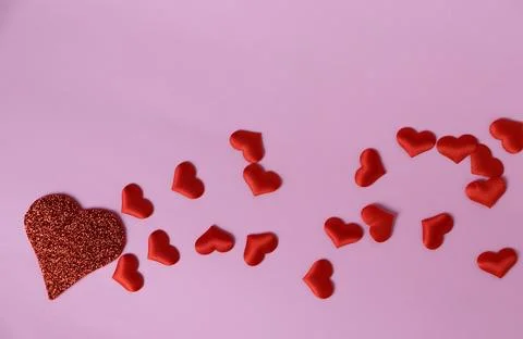 Red hearts on pink background create a playful arrangement for love and Stock Photos