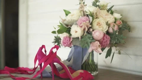 Red heels sit on a table with a beautiful flower vase. Stock Footage 135226648