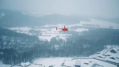 A red helicopter is flying over a snowy forest. Stock Footage 80319098