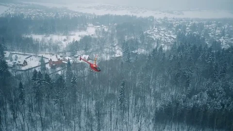 A red helicopter is flying over a snowy forest. Stock Footage 80319100