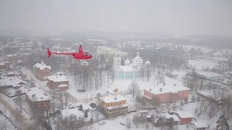 A red helicopter is flying over the snowy city. Stock Footage 80319101