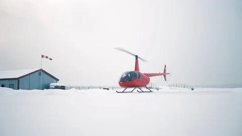A red helicopter takes off in a snow-covered field. Stock Footage 80319113
