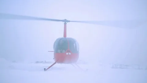 A red helicopter takes off in a snow-covered field. Stock Footage 80319129