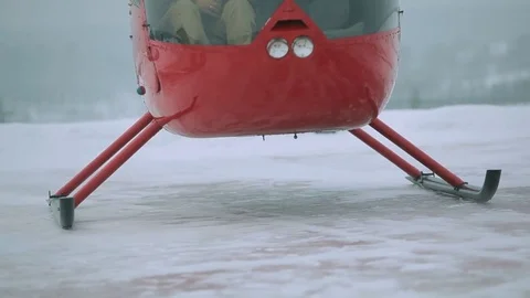 A red helicopter takes off in a snow-covered field. Stock Footage 80319142