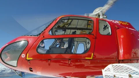 Red helicopter taking off from snowy mountain on sunny day in Iceland Stock Footage 124209332