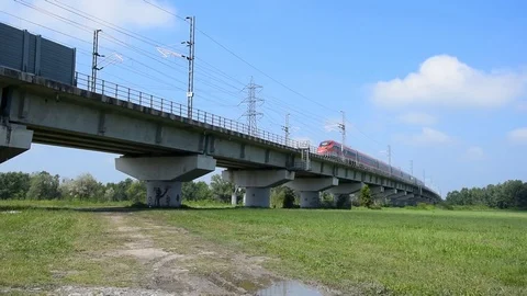 Red high speed train crossing a bridge over a field Stock Footage 107785125