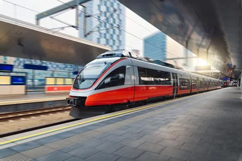 Red high speed train in motion on the railway station at sunset. Fast moder.. Stock Photos