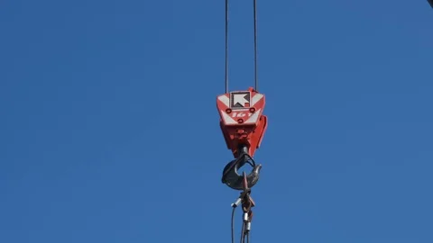 The red hook of a construction crane hanging down from a boom on a clear sky Stock Footage 123871750