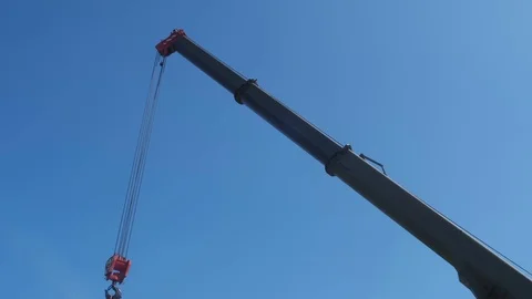 The red hook of a construction crane hanging down from a boom on a clear sky Stock Footage 123871791
