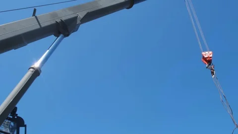 The red hook of a construction crane hanging down from a boom on a clear sky Stock Footage 123871820