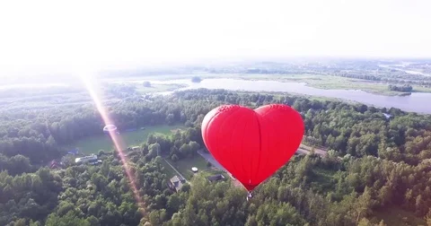 Red hot air balloon in the shape of a heart in the air. View around, aerial Video stock 71213613