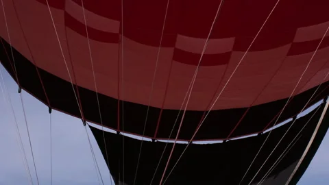 Red hot air balloon viewed from below with a visible flame inside 스톡 동영상 299689119