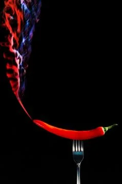 Red hot chilli pepper on fork with smoke Photos