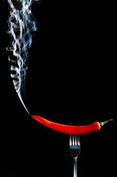 Red hot chilli pepper on fork with smoke Foto stock