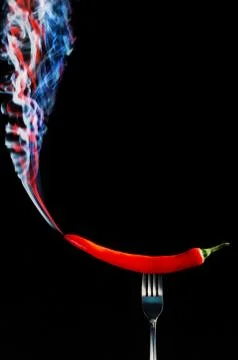 Red hot chilli pepper on fork with smoke Photos