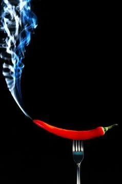 Red hot chilli pepper on fork with smoke Foto stock
