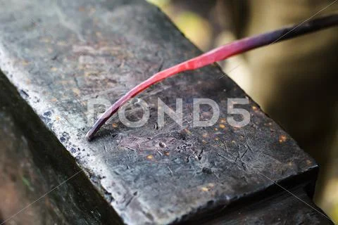 Red hot glowing steel rod on anvil close up Stock Photos
