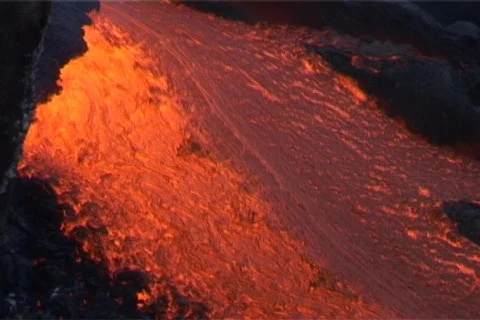 Red hot lava flows down a volcano  past blackened trees and Stock Footage 341107