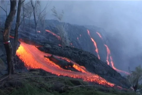 Red hot lava flows over a volcanic cone during an eruption in Видео 341102