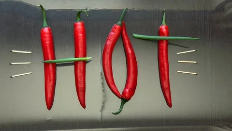 Red hot pepper and green onions laid out the word hot on the mirror surface Stockbeeldmateriaal 104061027
