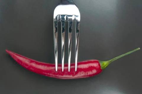 Red hot pepper with fork close-up on grey background. Healthy vegetable food  Foto stock