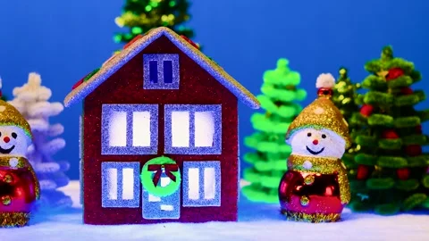 Red house with different lights in windows surrounded by two snowmen Stock-Footage 300992299